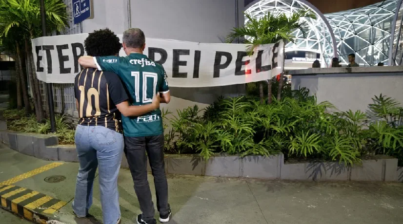 Dos hinchas del fútbol lamentan la muerte de Pelé afuera del hospital donde falleció.
