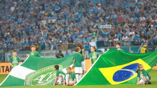 Niños sostienen las banderas de Brasil y Chapecoense antes de un partido entre Gremio y Atlético Mineiro de la Final de la Copa do Brasil. Foto: EFE.