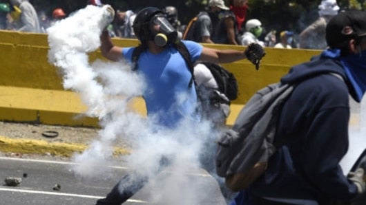 Manifestante devuelve un gas lacrimógeno disparado por la Policía. Foto: AFP