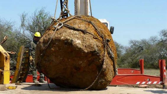 Un trabajador posa junto con el segundo meteorito más grande del mundo, que fue descubierto y extraído en la zona de Charata en la provincia de Chaco (Argentina). Foto Agencia EFE