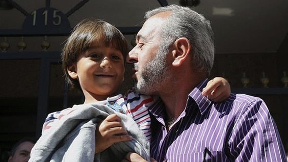 El refugiado sirio Osama Abdul Mohsen, junto a su hijo Zaid, a la salida de su nueva vivienda en Getafe. Foto: EFE.