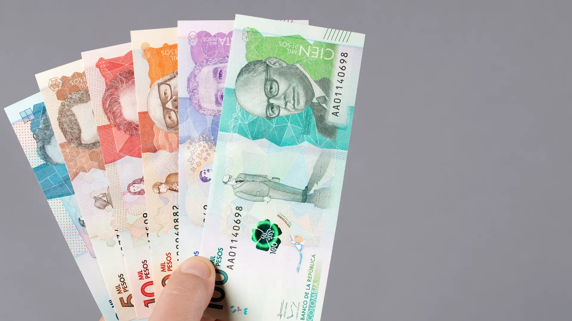 dinero-colombiano-en-la-mano-con-un-fondo-gris (1)